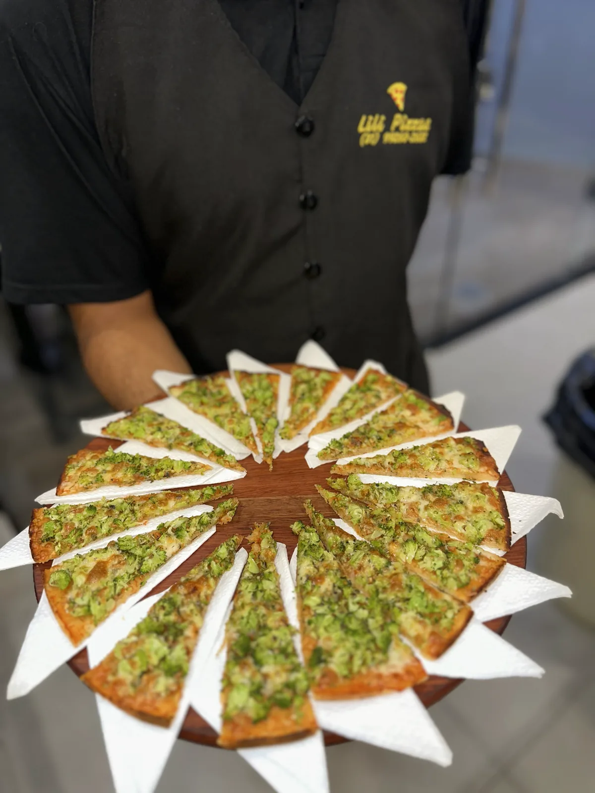 Pizzaiolo da Lili Pizzas de uniforme servindo pizza